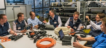 Работники igus сидят за столом с изделиями